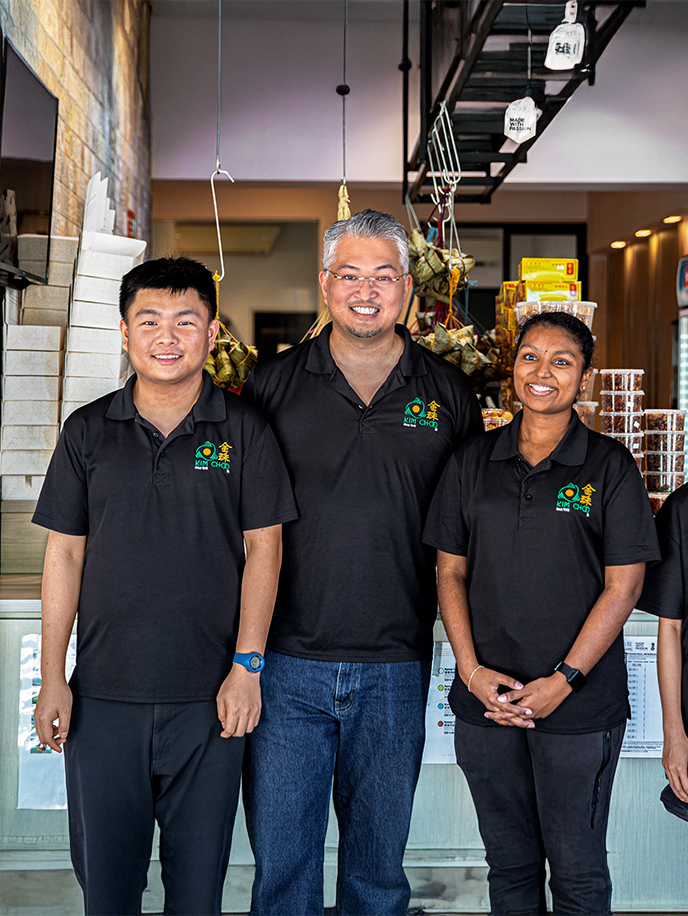Staff at Kim Choo Kueh Chang smiling together behind their shop counter